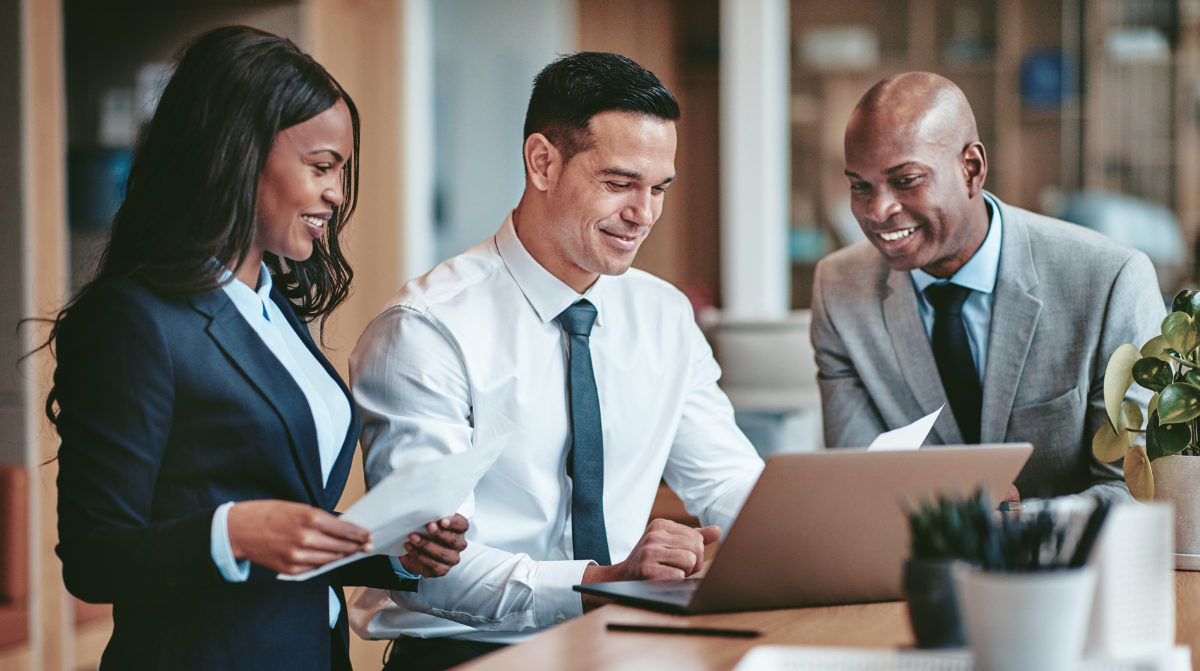 business professionals gathered around an office laptop