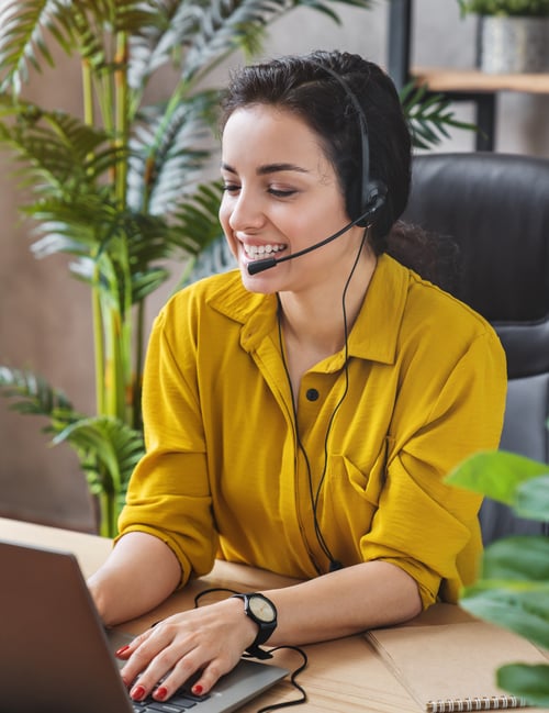 smiling woman at working laptop with headset