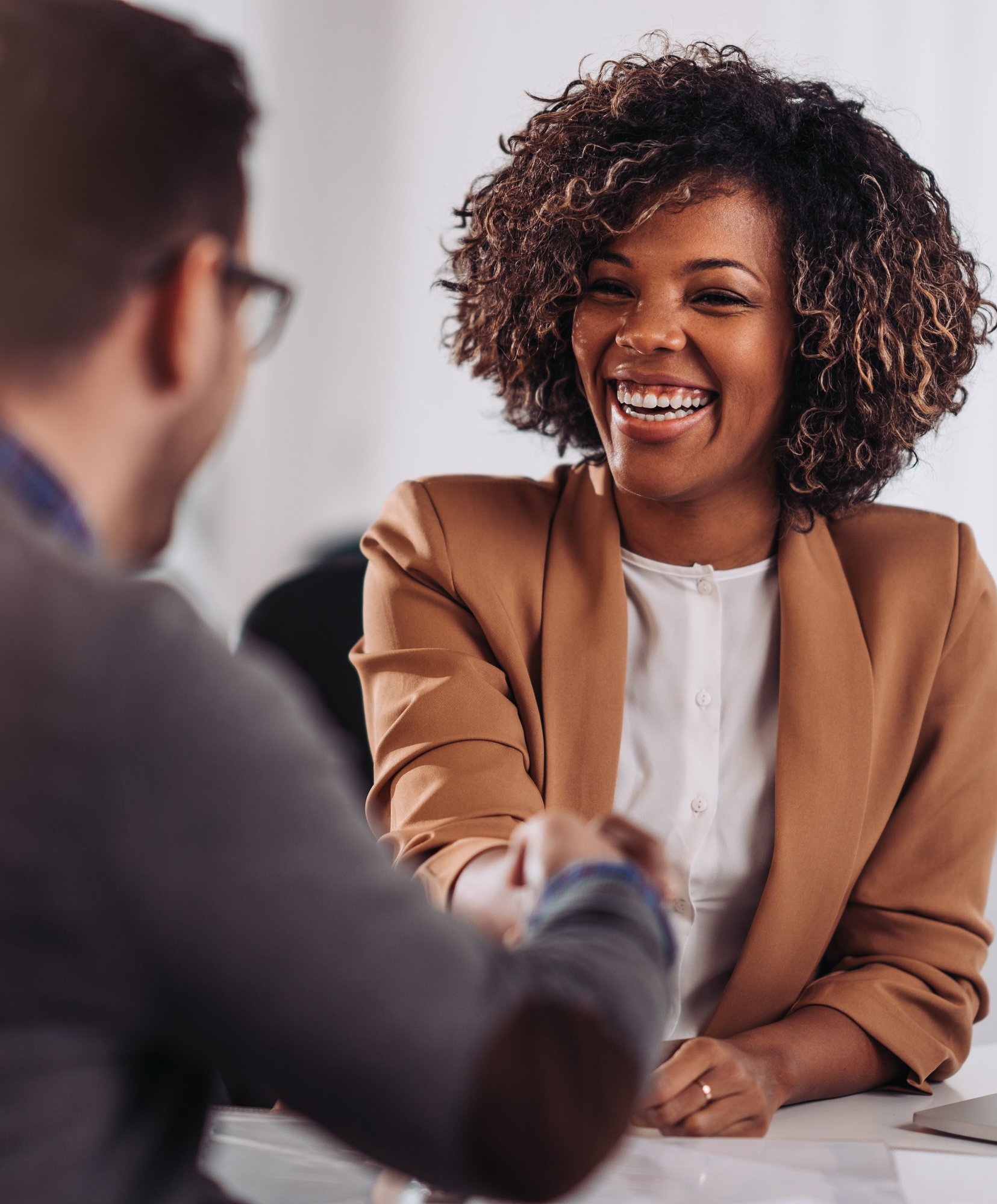 businesswoman smiling and shaking hands with business man