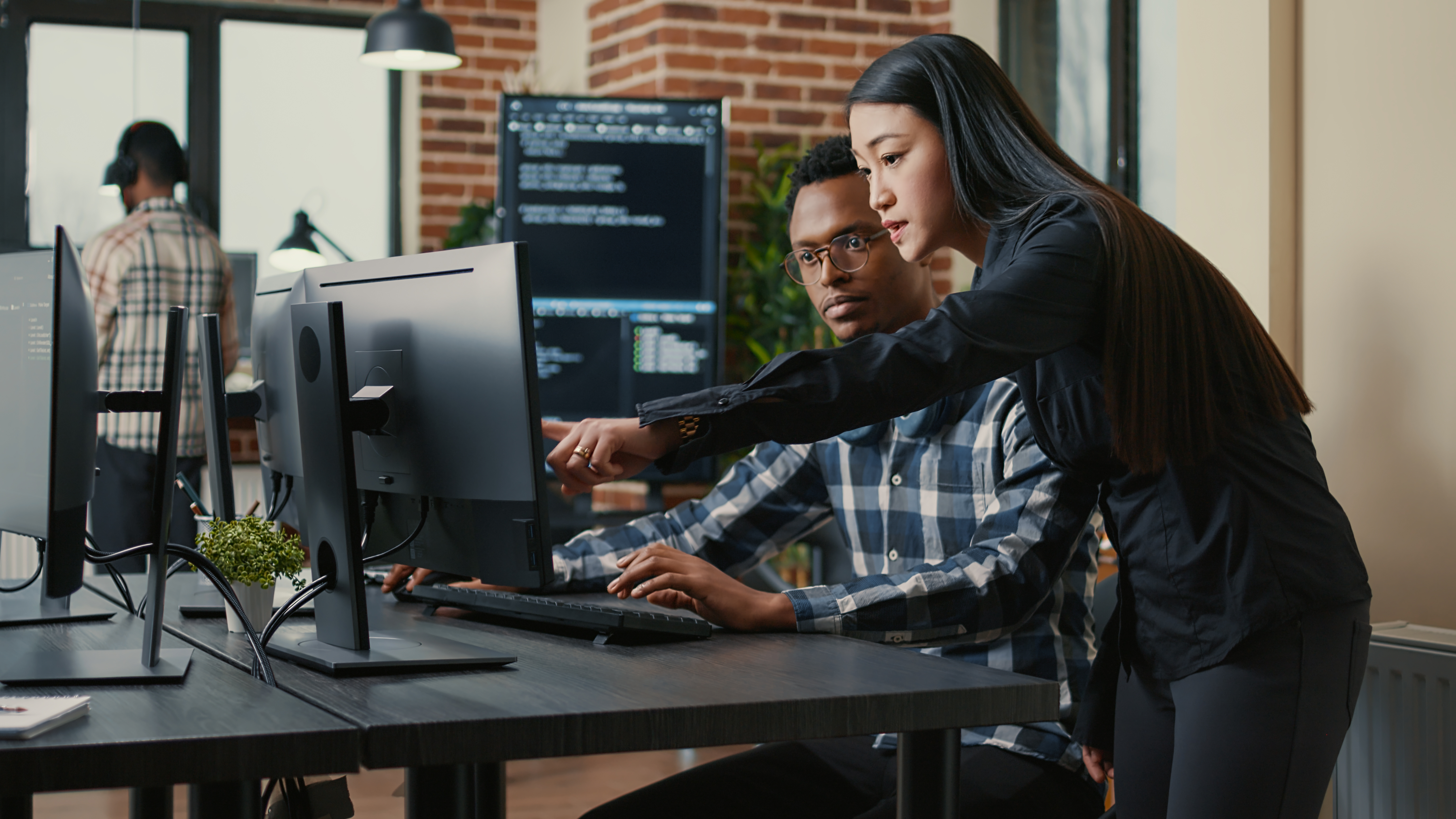 a man and a woman review code on a computer screen