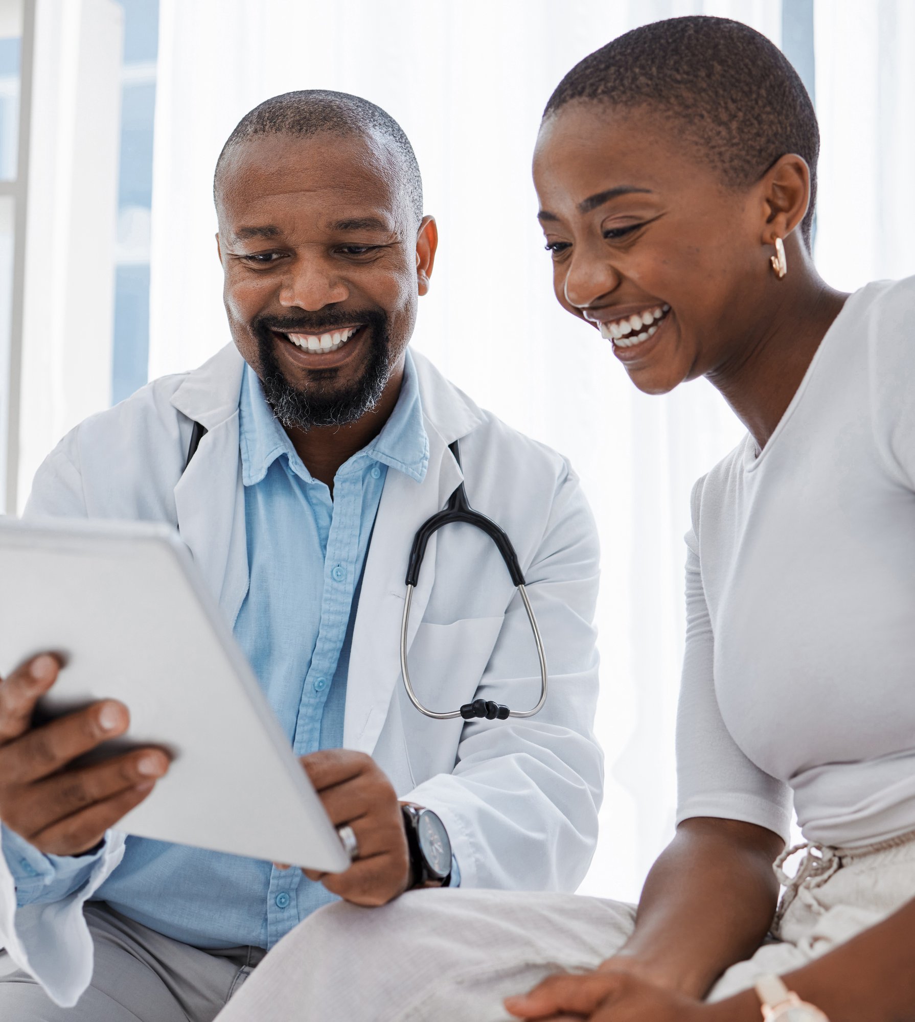 african american doctor and patient smiling looking at tablet
