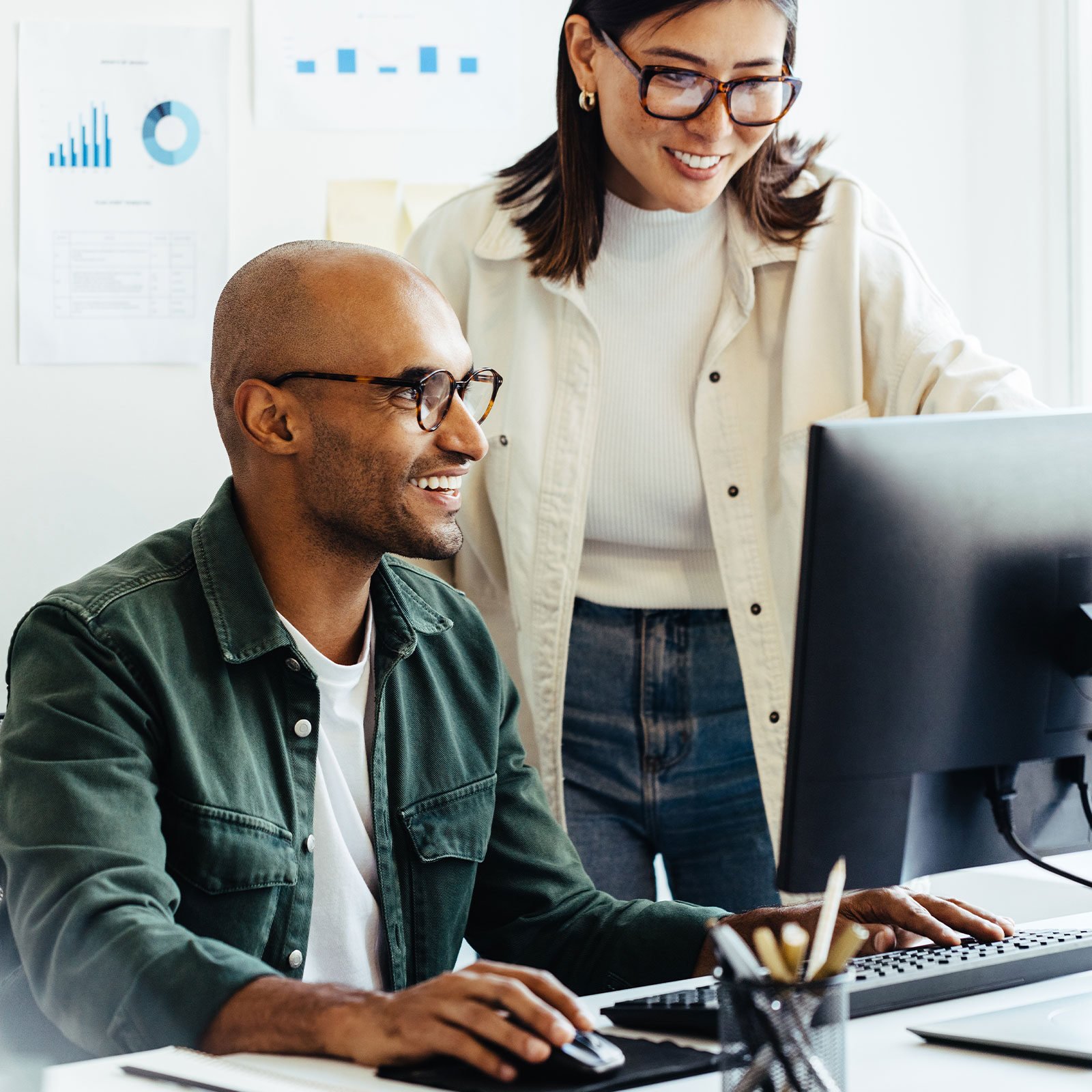 Coworkers smiling looking at computer screen together 