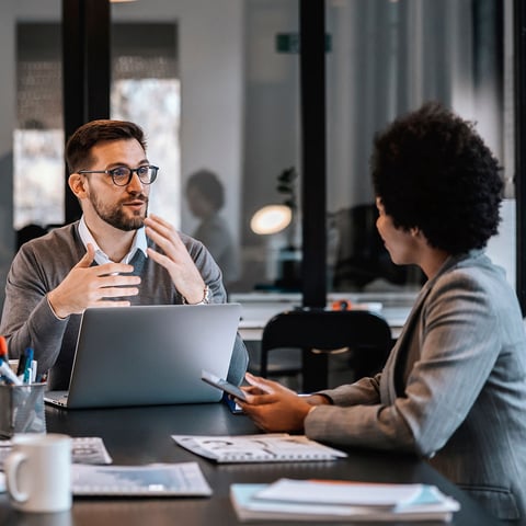 Co-workers sitting at table talking to each other